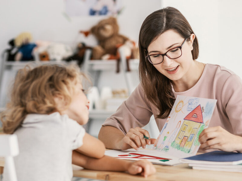 Speech therapist warmly engaging with a toddler during a play-based evaluation session